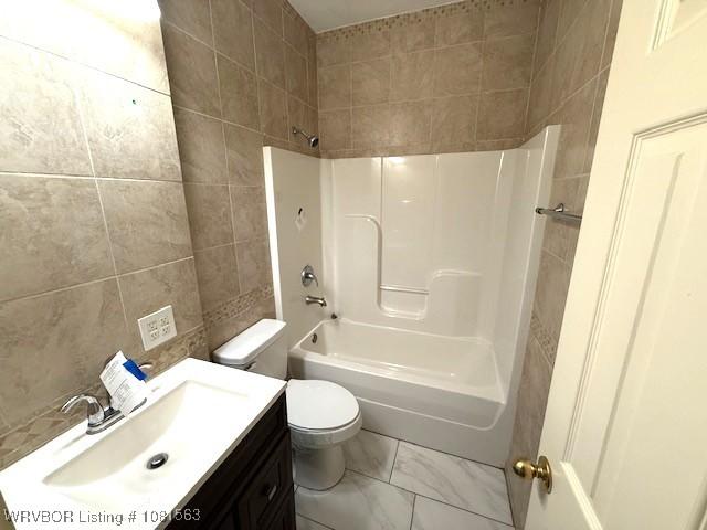 1434 W College St, Ozark, AR 72949 - bathroom with tile walls, toilet, vanity,  shower combination, and marble look tiles