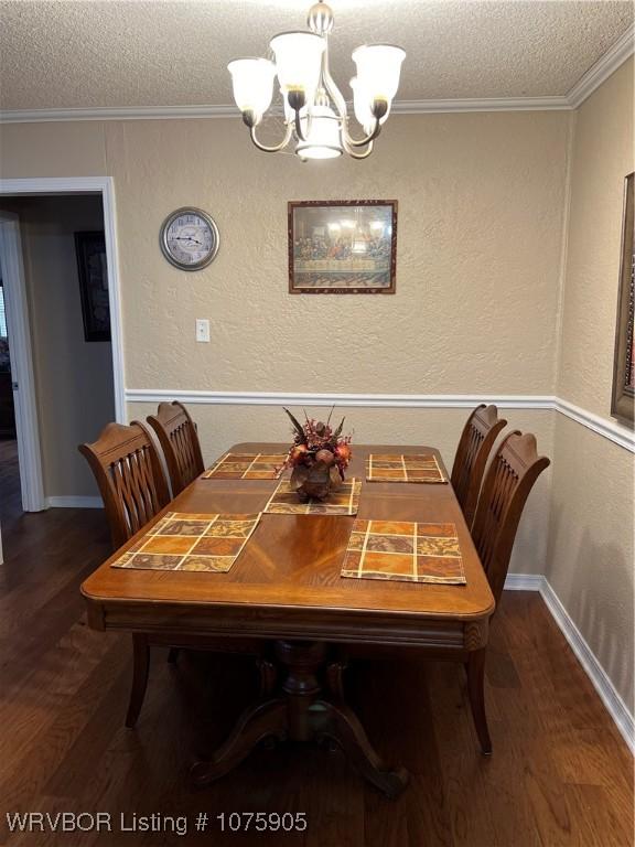 dining room featuring dark hardwood / wood-style flooring, ornamental molding, a textured ceiling, and a notable chandelier