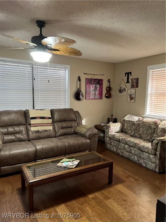 living room featuring wood-type flooring, a textured ceiling, and ceiling fan