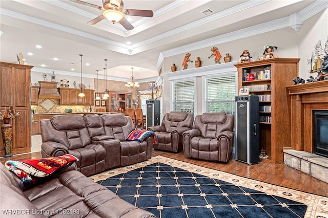 479872 E 1080th Rd, Muldrow, OK 74948 - living room with wood finished floors, a fireplace with raised hearth, ornamental molding, a ceiling fan, and a chandelier