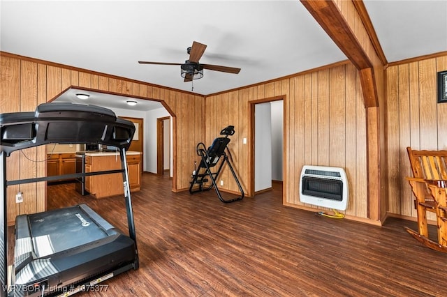 exercise area with ornamental molding, heating unit, ceiling fan, and dark wood-type flooring