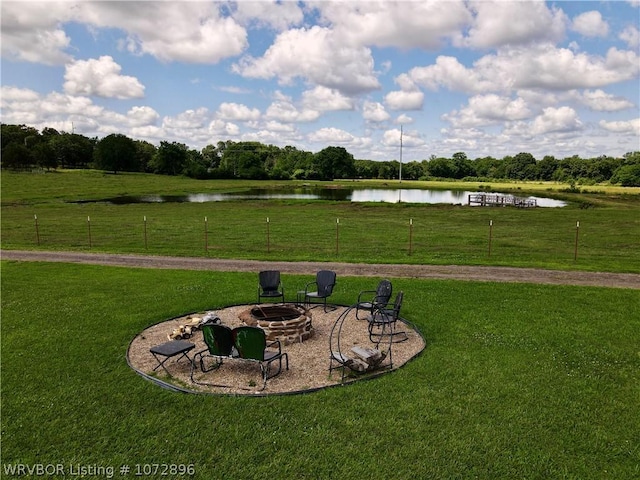 surrounding community with a fire pit, a water view, and a yard