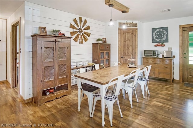 dining area featuring wood-type flooring and wood walls