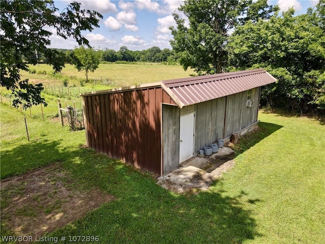 view of outbuilding featuring a rural view and a lawn