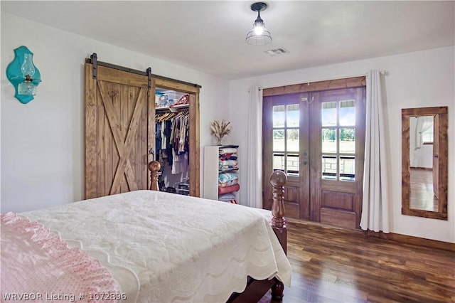 bedroom with a barn door, a closet, dark hardwood / wood-style floors, and french doors