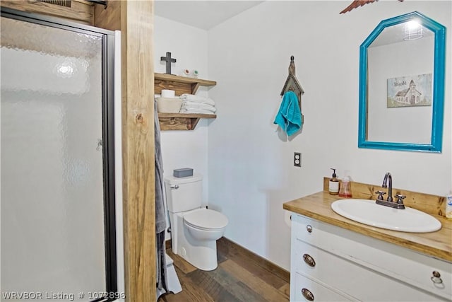 bathroom featuring wood-type flooring, vanity, toilet, and walk in shower