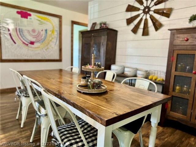 dining space with dark hardwood / wood-style floors and wooden walls