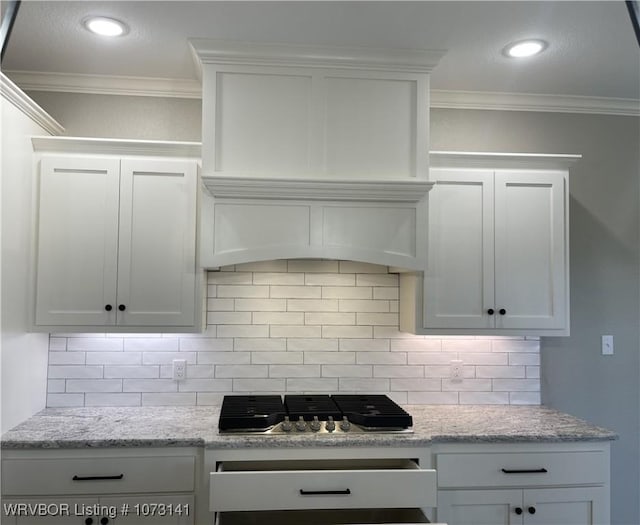 kitchen with white cabinetry, light stone countertops, stainless steel gas cooktop, decorative backsplash, and ornamental molding