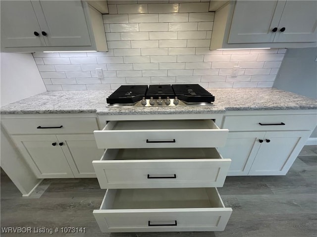 kitchen with white cabinetry, light stone countertops, and tasteful backsplash