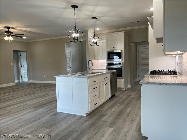 kitchen with hanging light fixtures, tasteful backsplash, an island with sink, white cabinets, and appliances with stainless steel finishes