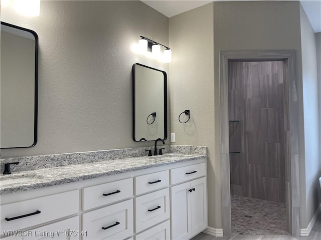 bathroom with vanity and a tile shower