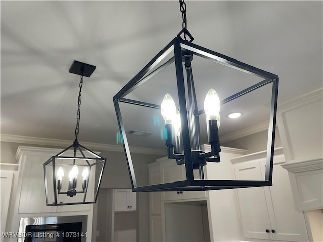 interior details featuring crown molding, white cabinets, and an inviting chandelier