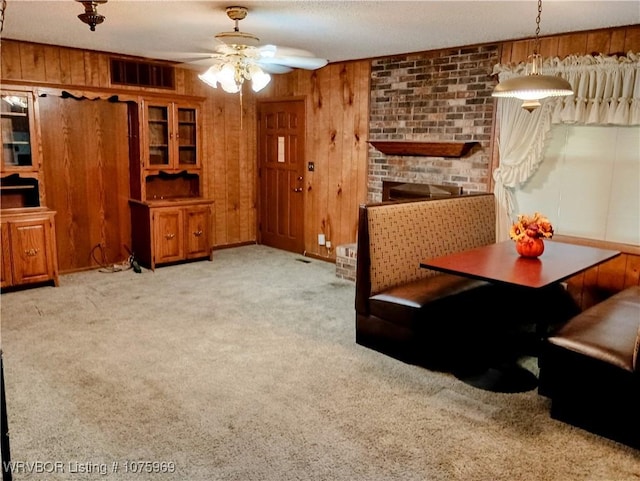 carpeted living room featuring ceiling fan and wooden walls