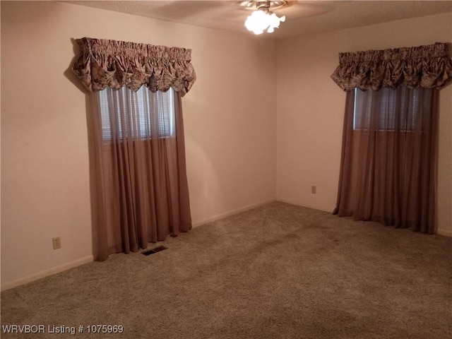 unfurnished room with ceiling fan and carpet