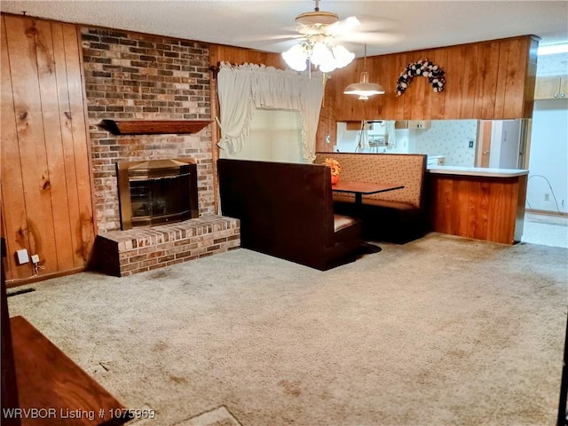 carpeted living room featuring wood walls, a fireplace, and ceiling fan