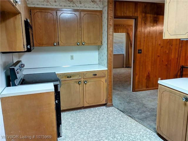 kitchen with wood walls, black appliances, and light carpet