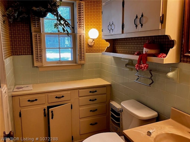 bathroom with vanity, tile walls, and toilet