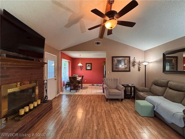 2114 Breckenridge Ter, Greenwood, AR 72936 - living room featuring wood finished floors, a textured ceiling, a brick fireplace, ceiling fan, and baseboards