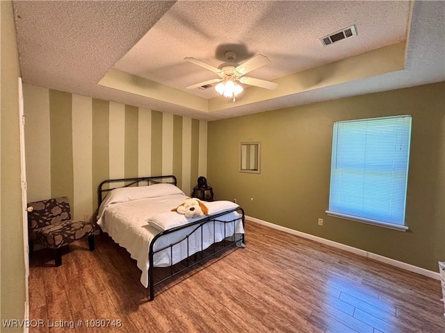 2114 Breckenridge Ter, Greenwood, AR 72936 - bedroom featuring a textured ceiling, a raised ceiling, wood finished floors, baseboards, and wallpapered walls