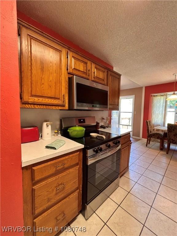 2114 Breckenridge Ter, Greenwood, AR 72936 - kitchen with stainless steel appliances, brown cabinetry, light countertops, light tile patterned floors, and a textured ceiling