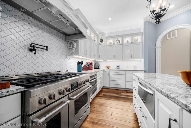 kitchen with tasteful backsplash, white cabinets, ornamental molding, and appliances with stainless steel finishes