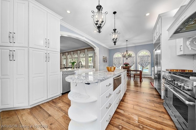 kitchen with white cabinetry, a center island, hanging light fixtures, premium appliances, and custom range hood