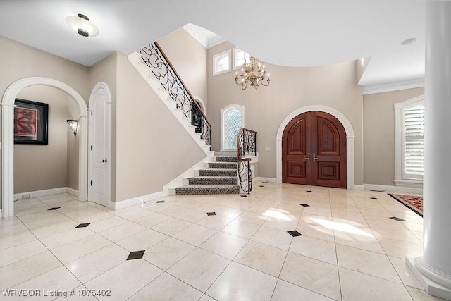 tiled foyer entrance featuring crown molding, a healthy amount of sunlight, and a notable chandelier