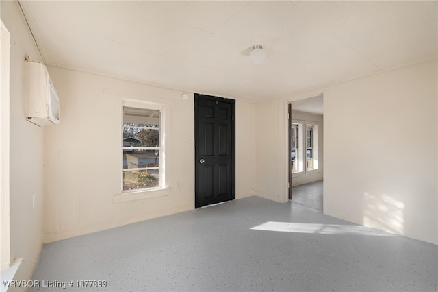 unfurnished room featuring a wall mounted AC and a wealth of natural light