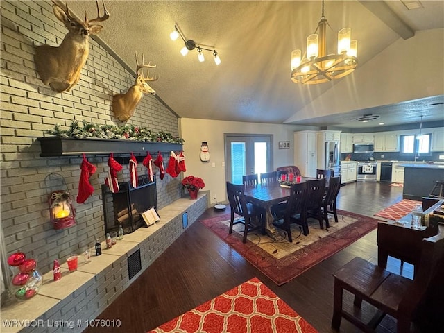 dining room with hardwood / wood-style floors, lofted ceiling with beams, a textured ceiling, brick wall, and a chandelier