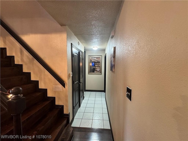 hallway with light tile patterned floors and a textured ceiling