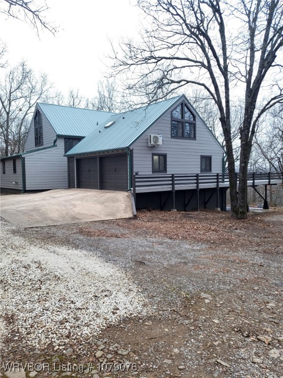 chalet / cabin with concrete driveway, metal roof, and an attached garage