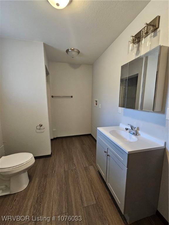 bathroom featuring vanity, toilet, wood-type flooring, and a textured ceiling