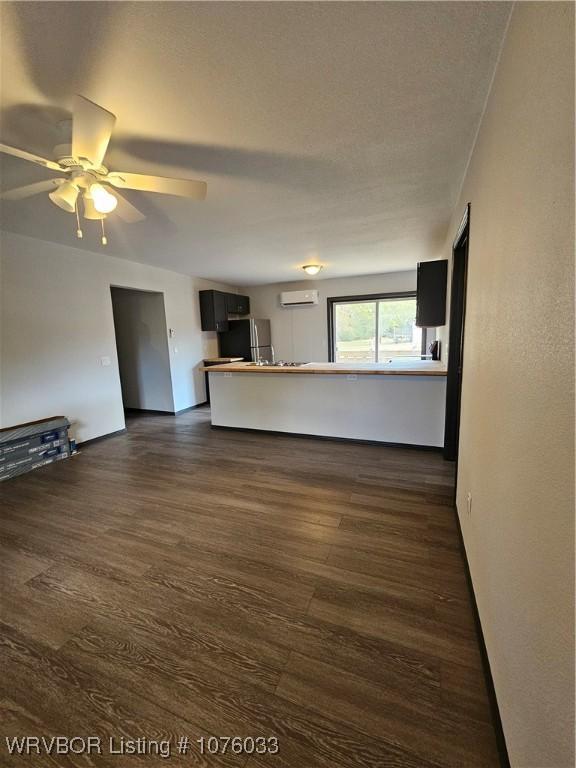 unfurnished living room featuring dark hardwood / wood-style floors, a wall unit AC, and ceiling fan