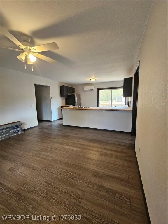 unfurnished living room with ceiling fan, a wall mounted air conditioner, and dark hardwood / wood-style floors