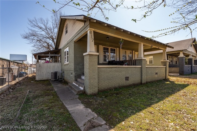 view of front of home featuring brick siding, central AC, and fence