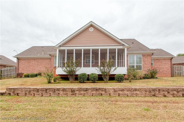 rear view of property featuring a yard and a sunroom