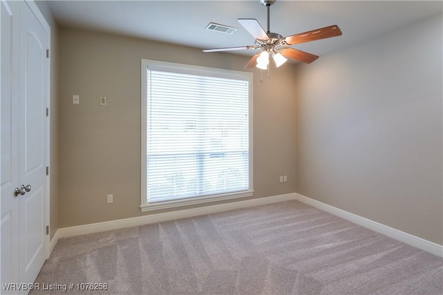 carpeted spare room featuring ceiling fan and plenty of natural light