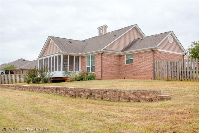 rear view of property with a sunroom and a yard