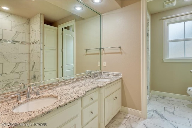 bathroom with vanity, toilet, a shower, and tasteful backsplash