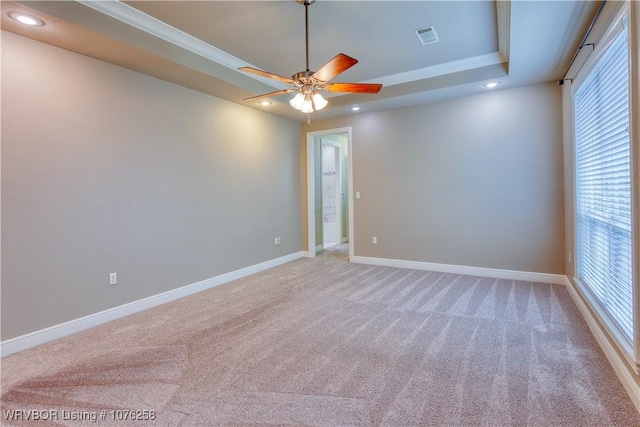 carpeted empty room with a tray ceiling, ceiling fan, and ornamental molding