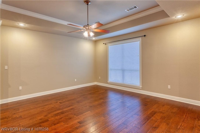 unfurnished room with ceiling fan, crown molding, dark wood-type flooring, and a tray ceiling