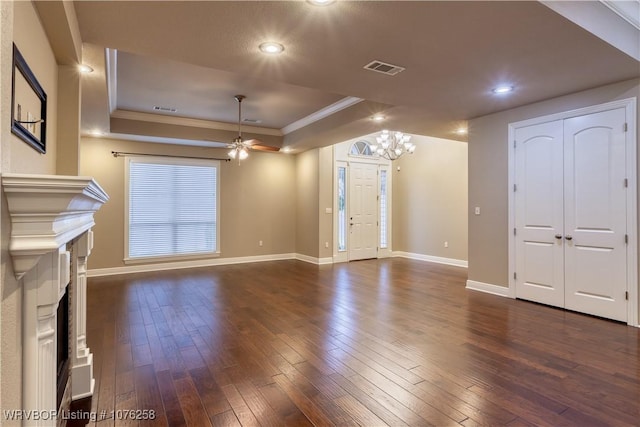 unfurnished living room with dark hardwood / wood-style floors, a raised ceiling, ornamental molding, and ceiling fan with notable chandelier