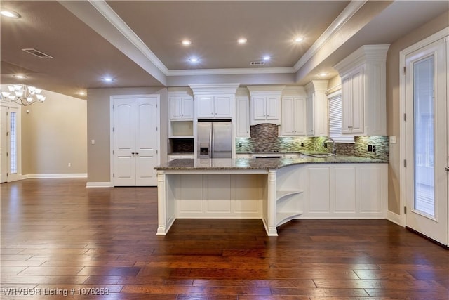 kitchen featuring stainless steel fridge, sink, dark stone countertops, a chandelier, and white cabinetry