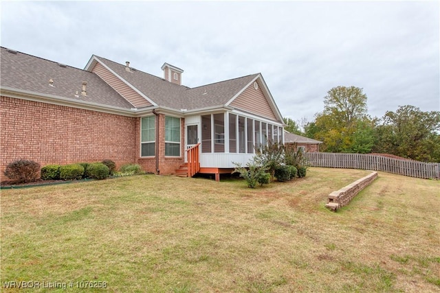 rear view of property with a sunroom and a lawn