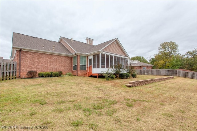 back of property featuring a lawn and a sunroom