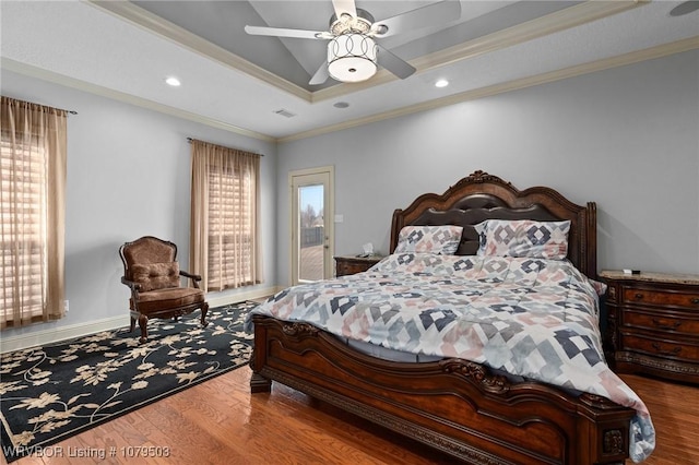 bedroom with a tray ceiling, wood finished floors, and ornamental molding