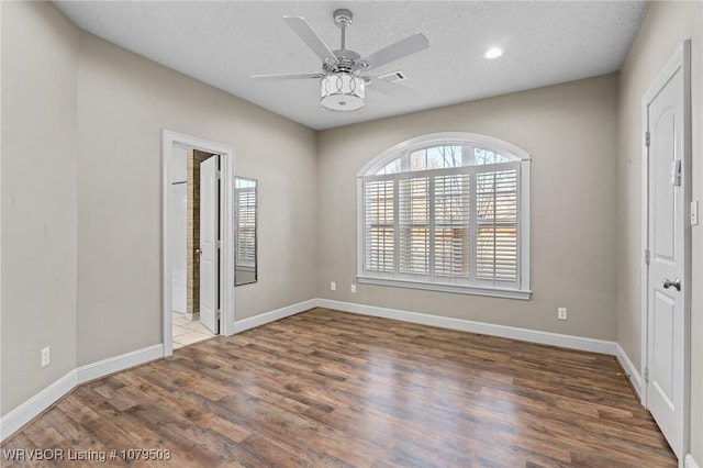 unfurnished bedroom with a textured ceiling, baseboards, and wood finished floors