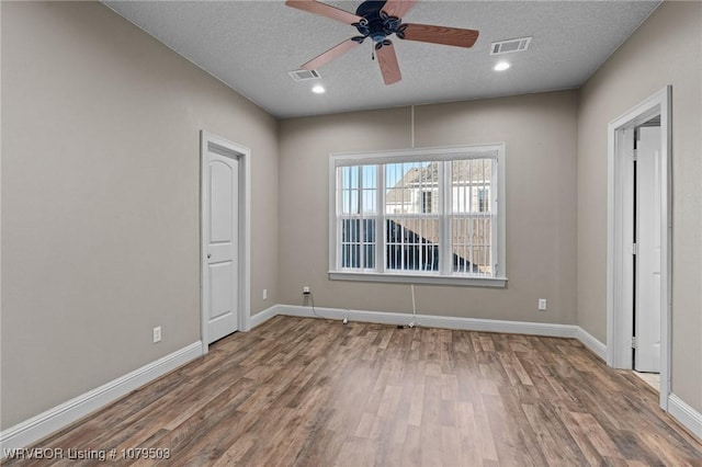 unfurnished room featuring wood finished floors, visible vents, and baseboards