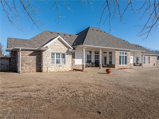 back of house featuring stone siding, fence, a shingled roof, ceiling fan, and a patio area