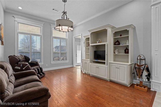 living area featuring visible vents, baseboards, ornamental molding, an inviting chandelier, and light wood-style floors